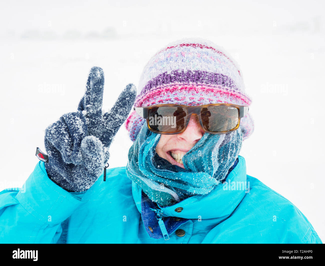 Smiling woman making peace du geste dans la neige Banque D'Images