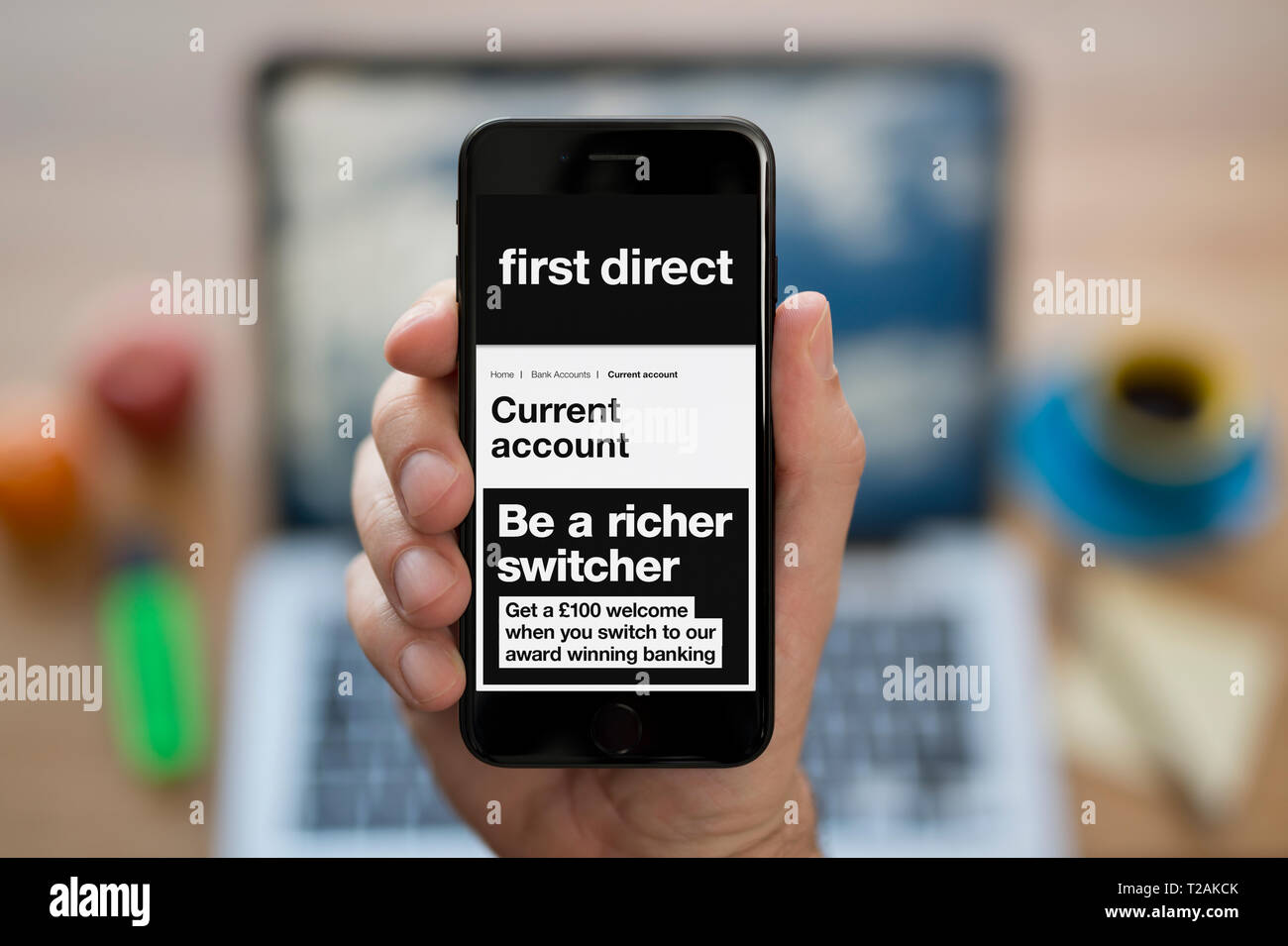 Un homme se penche sur son iPhone qui affiche le premier logo Direct (usage éditorial uniquement). Banque D'Images