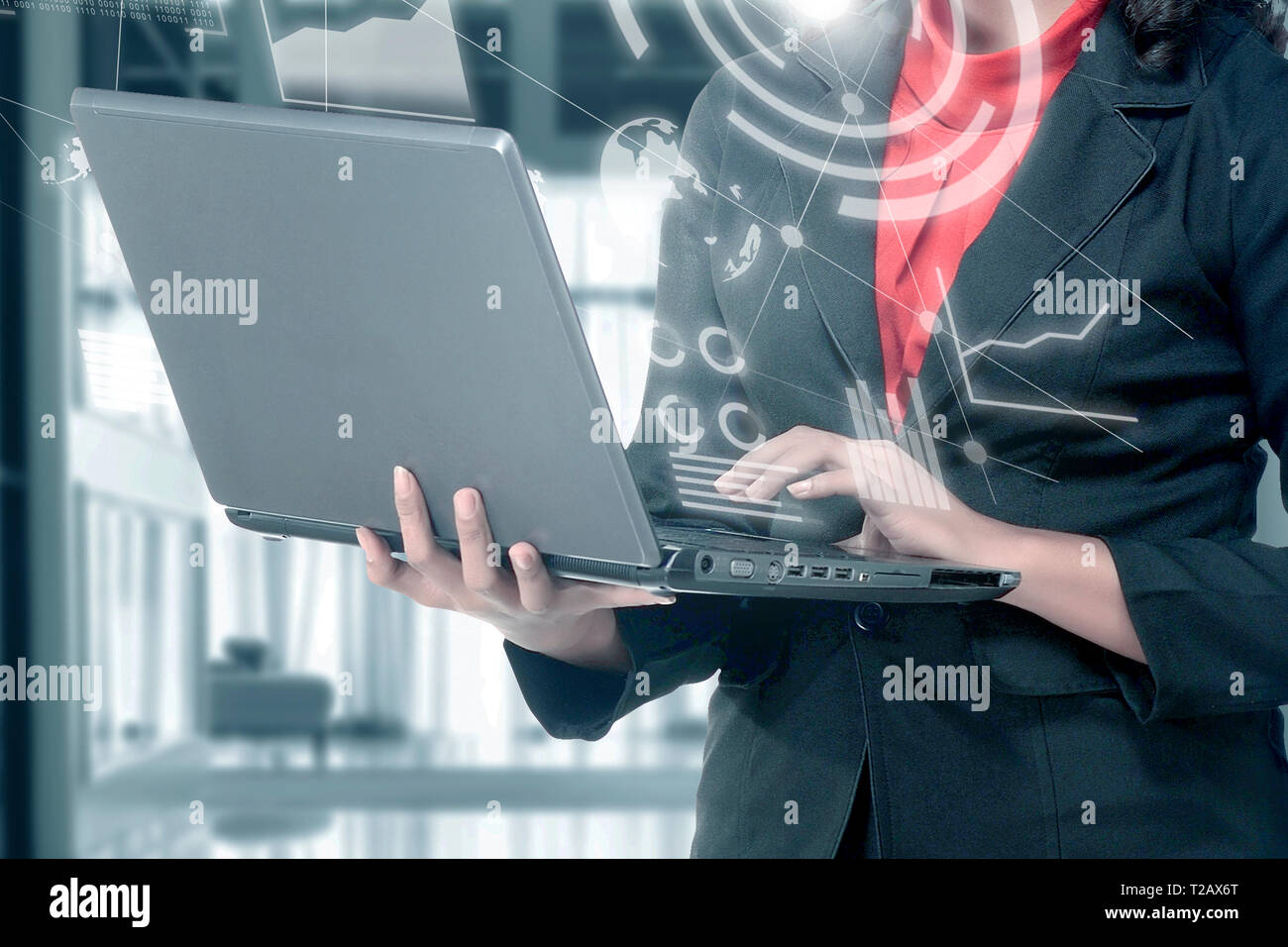 Business Woman holding laptop avec sa main avec un écran virtuel qui affiche l'interface de tableau financier et cartes du monde. La technologie numérique conc Banque D'Images