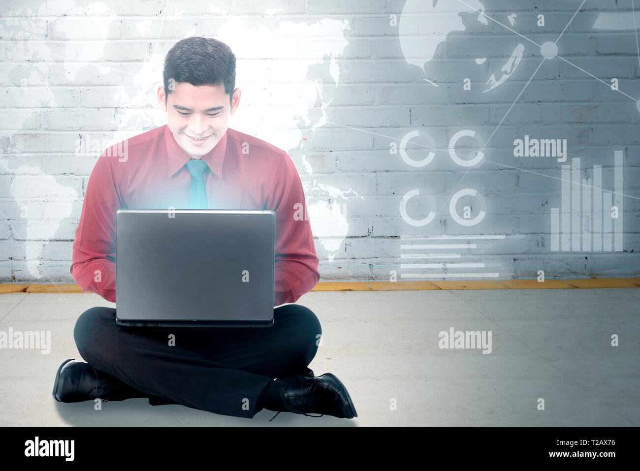 Smiling asian businessman sitting et l'aide d'un ordinateur portable avec écran virtuel qui l'affichage de l'interface graphique et cartes du monde financier. Les technologies numériques Banque D'Images