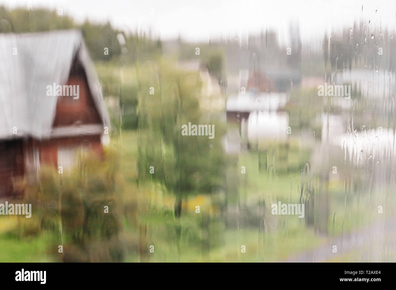 Vue de la maison en bois de la fenêtre humide sur un jour de pluie, flou, flou photo Banque D'Images