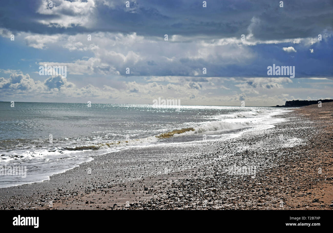 Belle vue sur la mer des vagues se brisant sur la plage de galets avec un ciel nuageux le long de la côte du Kent Banque D'Images