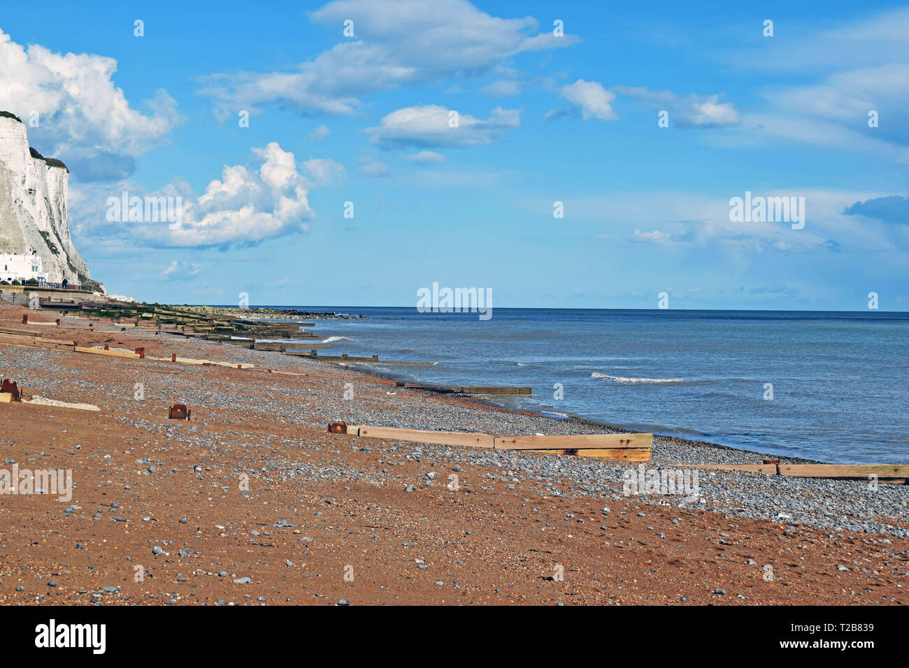 Scène de la mer à Saint Margaret's Bay, le ciel nuageux spectaculaires sur la mer bleue et des éperons de la mer sur la plage de galets avec les falaises en arrière-plan Banque D'Images