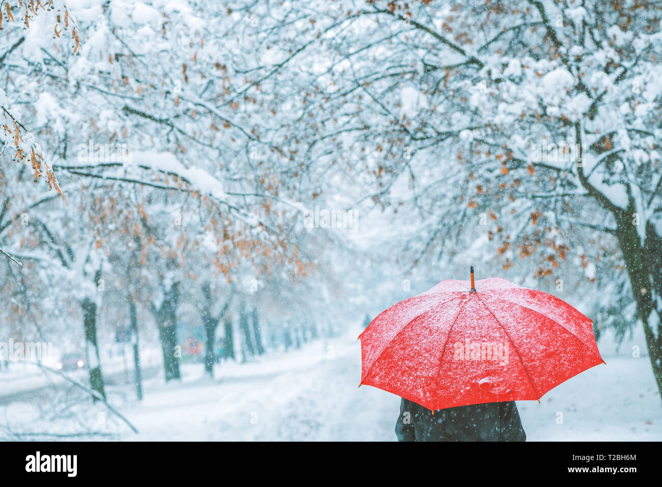 Femme sous parapluie rouge dans la neige profiter de la première neige de la saison d'hiver Banque D'Images