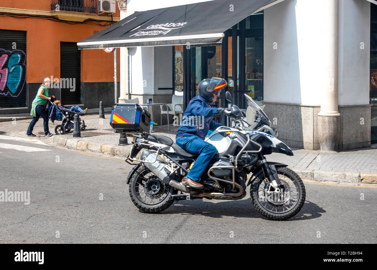 Femme poussant un landau et un homme sur une moto Banque D'Images