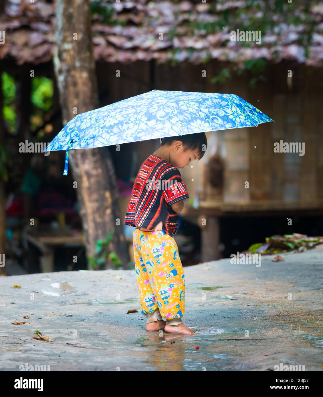 Baan Tong Luang Chiang Mai THAÏLANDE 16 Avril 2018 jeune garçon joue dans la flaque d'eau de pluie Vie Tribal Village Karen Banque D'Images