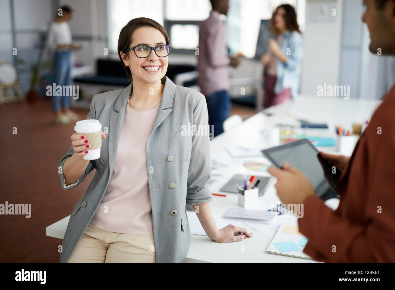 Portrait of young businesswoman smiling heureusement réussi tout en parlant à collègue pendant pause café dans office, copy space Banque D'Images
