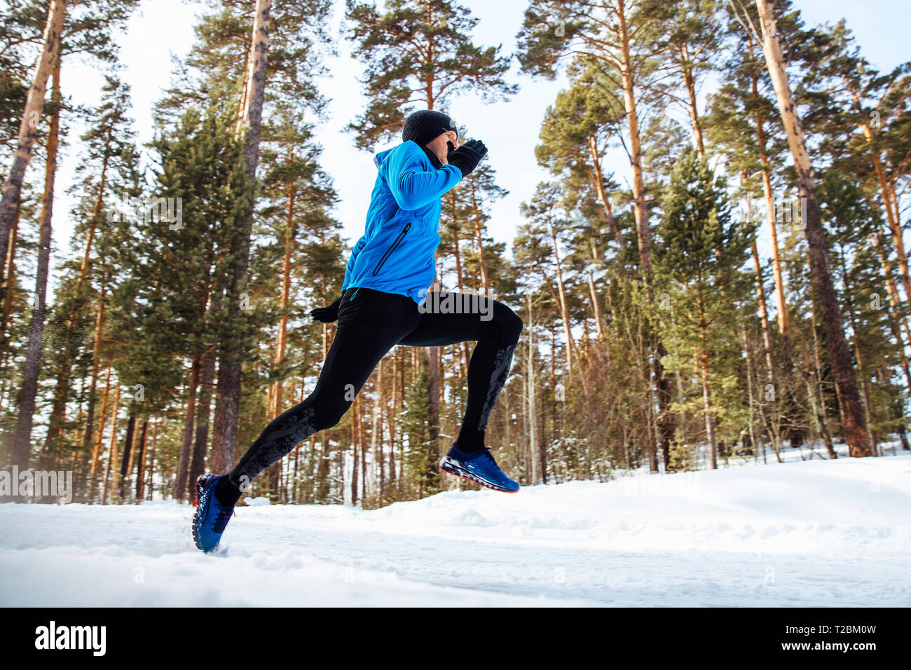 L'homme sportif runner fonctionnant en hiver la forêt enneigée Banque D'Images