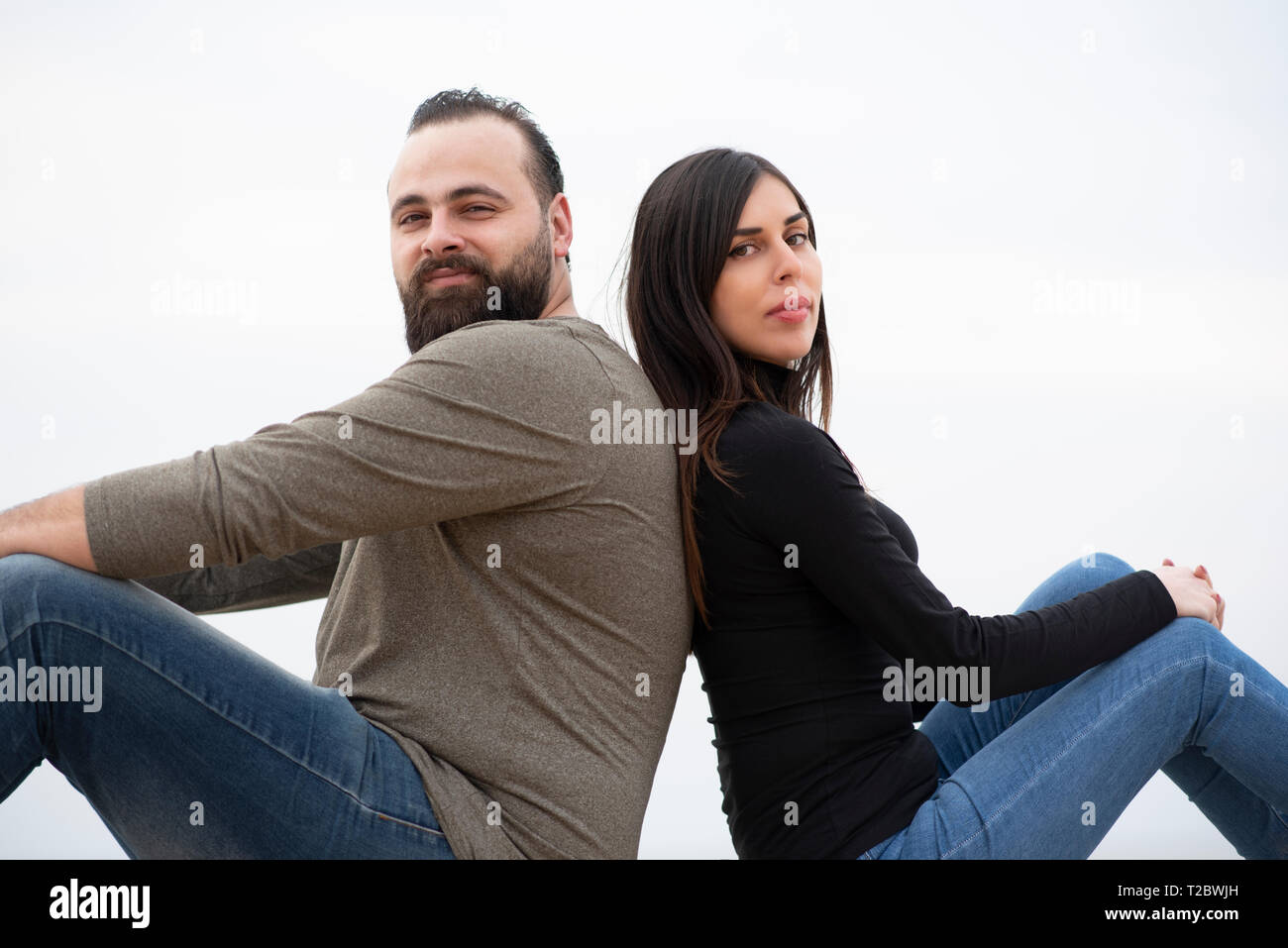 Mand et femme assise dos à dos sur la plage Banque D'Images