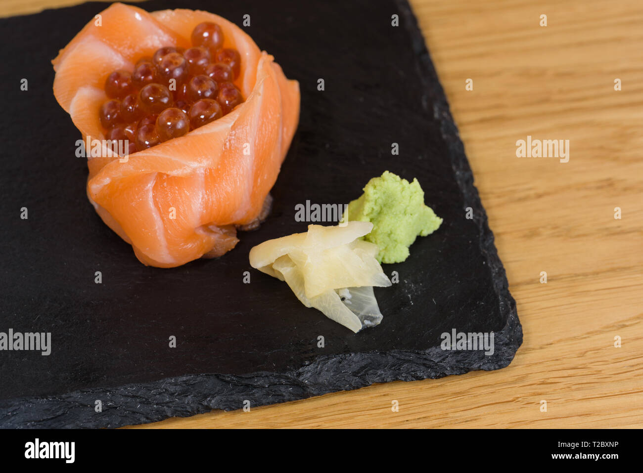 Composition de la nourriture pour poissons, les filets de saumon monté sous la forme d'une tasse, farcie de caviar, servi de plaque sur une dalle d'ardoise, garni d'un gingembre Banque D'Images