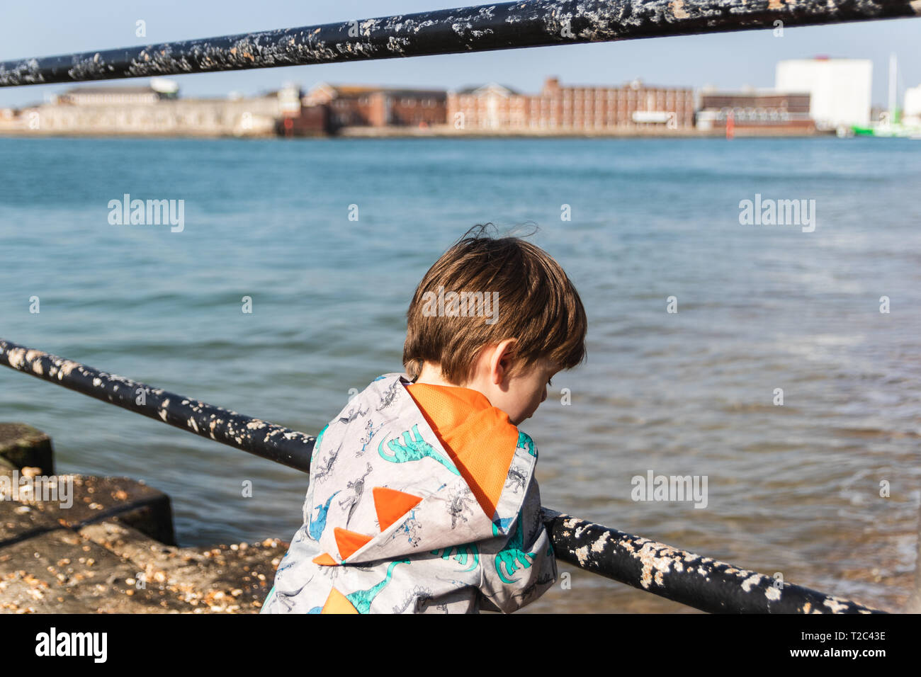 Jeune garçon penché sur une balustrade à à l'eau ci-dessous Banque D'Images