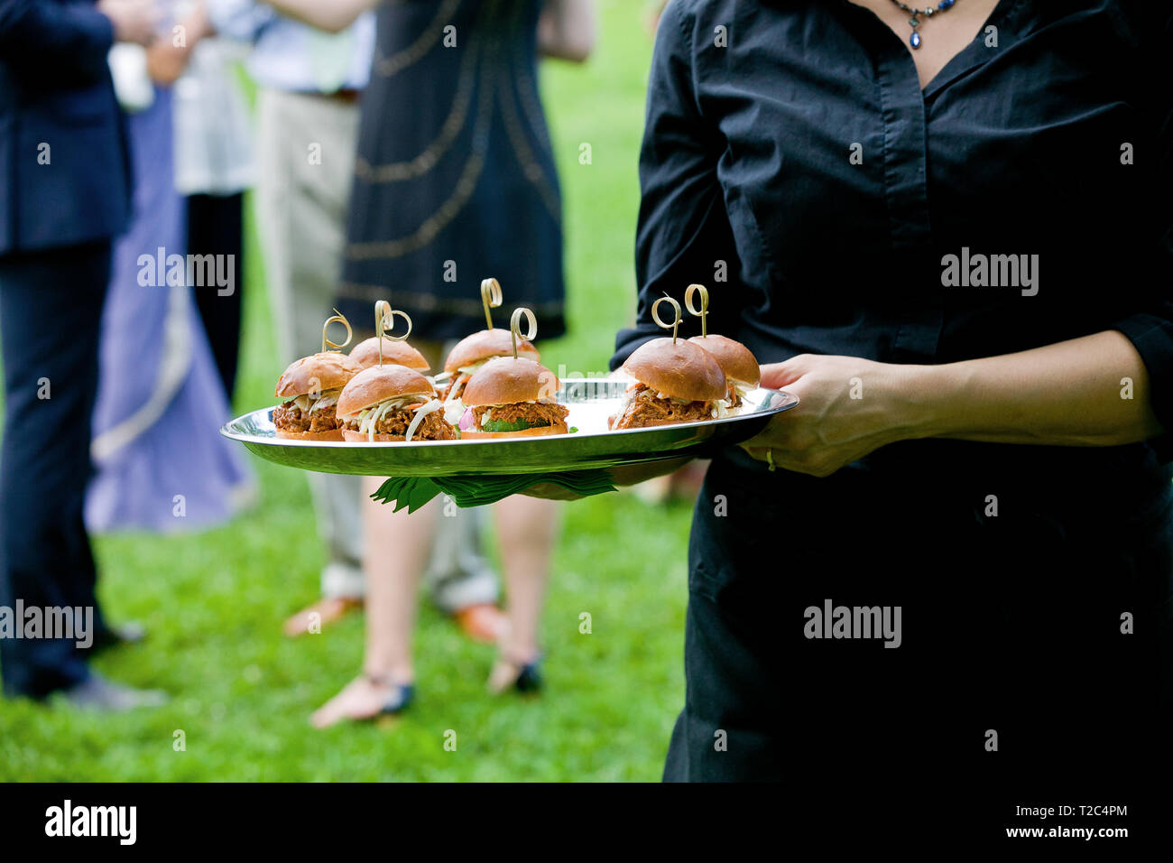 Un serveur qui contient un bac plein de mini sandwiches de porc lors d'un événement Banque D'Images