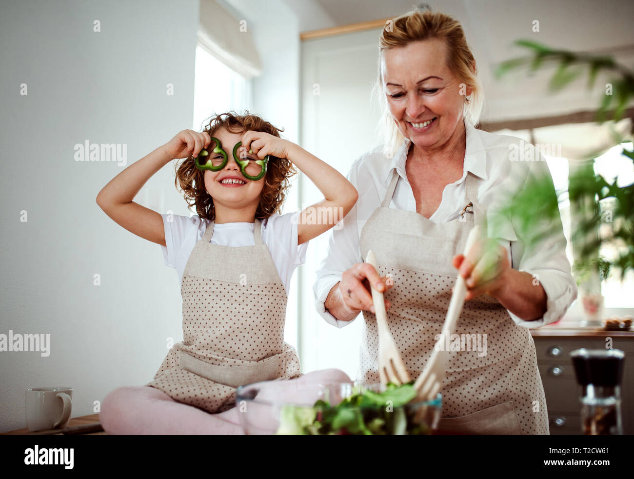 Un portrait de petite fille heureuse avec grand-mère de préparer une salade de légumes à la maison, avoir du plaisir. Banque D'Images