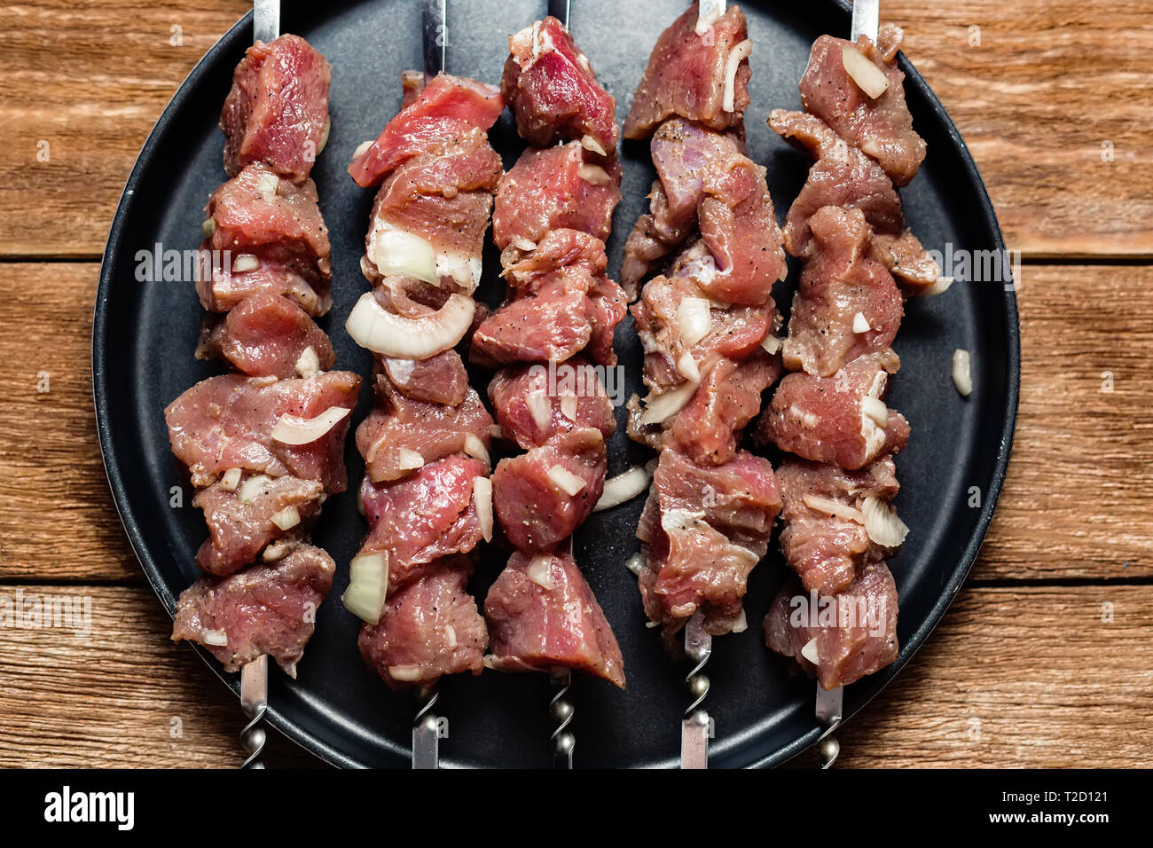 Un certain nombre de brochettes de viande exposée dans une plaque noire. Close-up de morceaux de boeuf prêt à fry. Plat de viande. Vue de dessus sur un background Banque D'Images