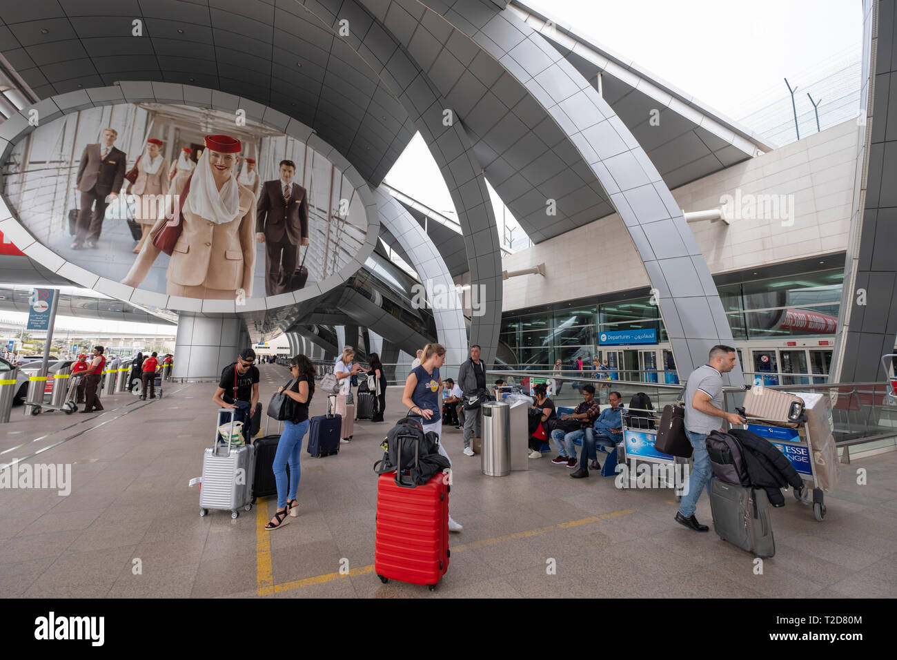 Les passagers avec un rouleau cas entrant dans l'aérogare de départ à l'Aéroport International de Dubaï en Émirats Arabes Unis Banque D'Images