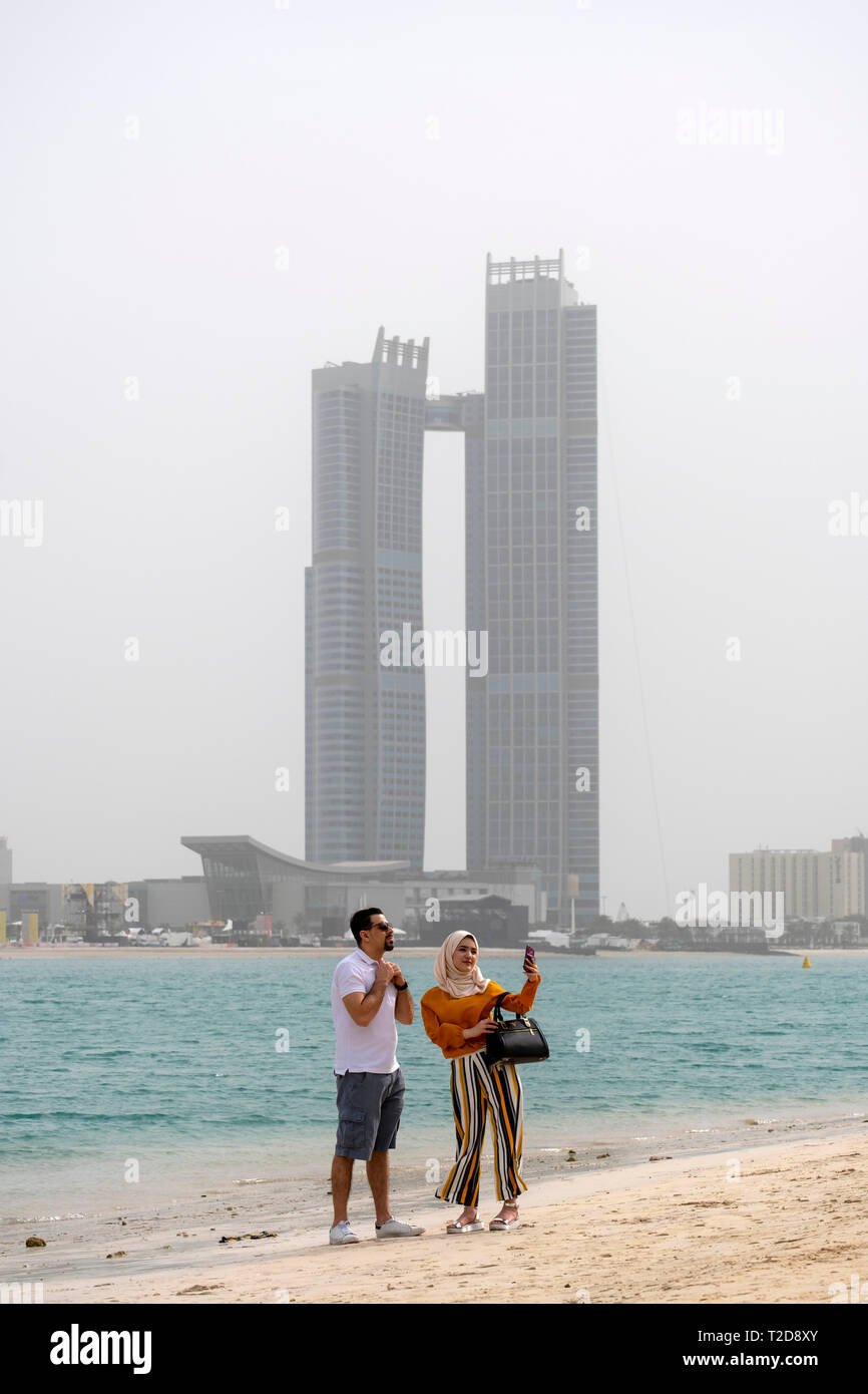 Jeune femme musulmane portant un hijab en tenant un avec un homme selfies sur une plage à Abu Dhabi, Émirats Arabes Unis Banque D'Images
