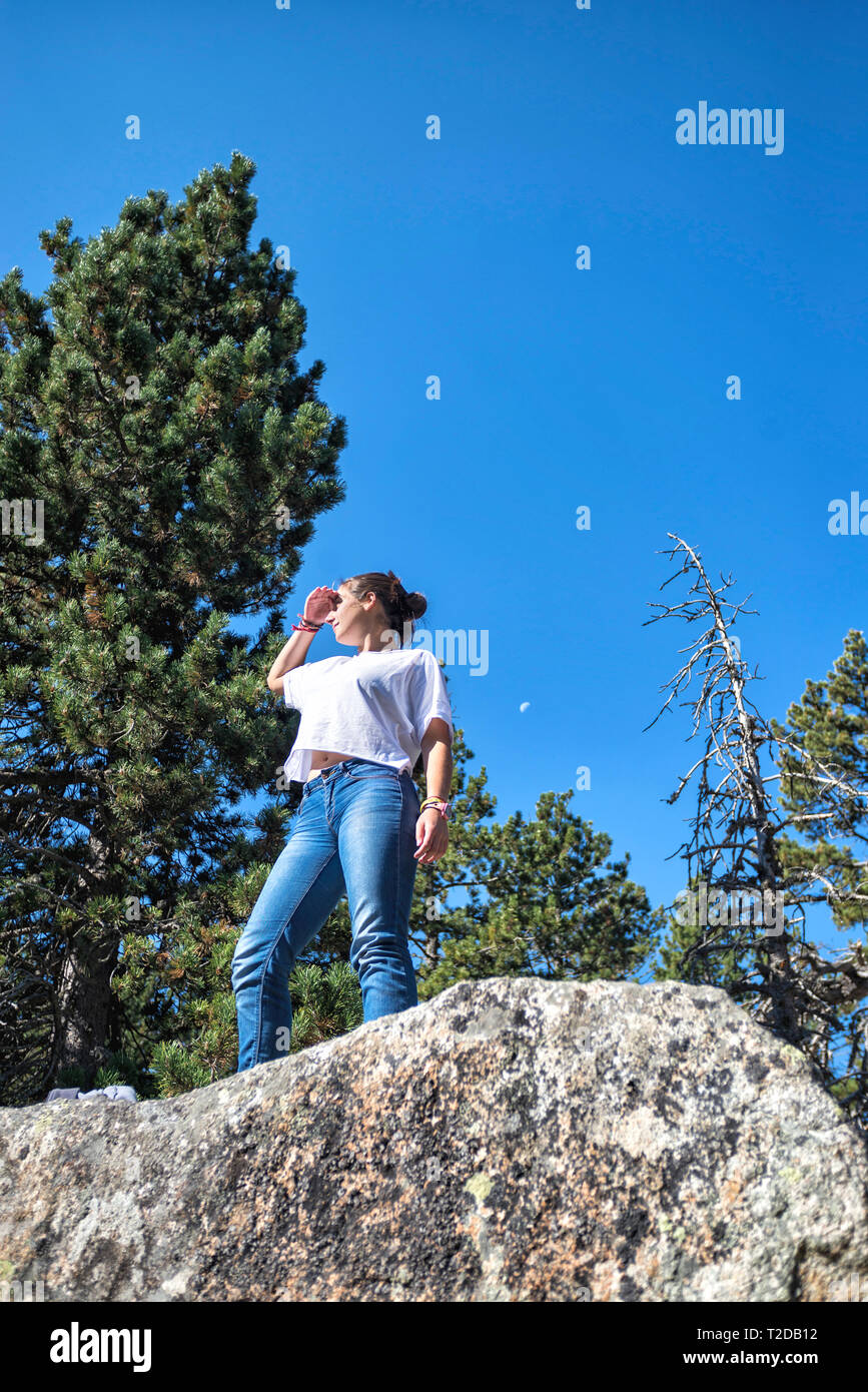 Jeune femme debout sur des rochers à l'extérieur contre ciel bleu Banque D'Images