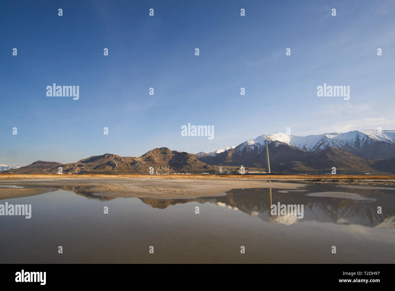 La Garfield la cheminée de la fonderie fonderie de Rio Tinto Kennecott reflète dans une piscine de marée sur la plage sur la rive sud du Grand Lac Salé, Utah, USA Banque D'Images