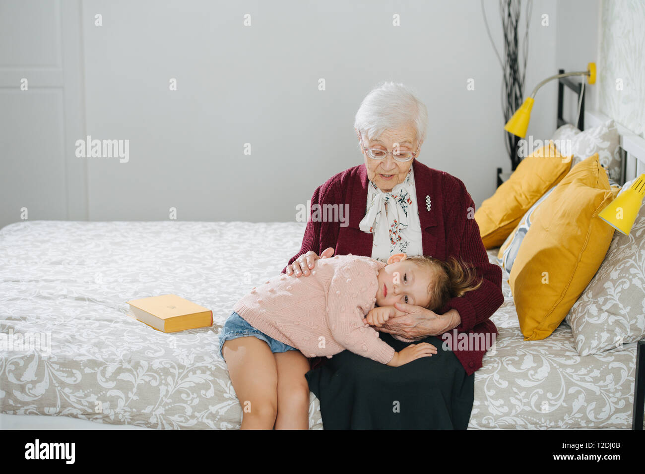 Senior lady passer du temps de qualité avec son arrière petite-fille. Restless petite fille espiègle bod ennuyer essayer de faire une sieste et ne veut pas dire que ce soit facile. Banque D'Images