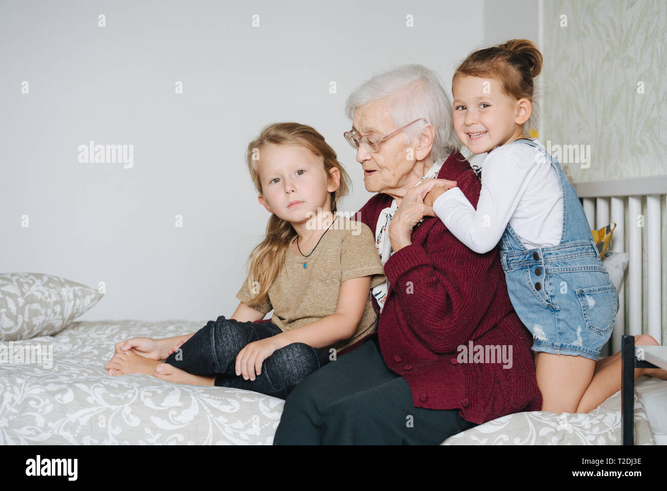 Des moments heureux avec grand-mère, la haute dame passer du temps de qualité entourée de ses petits grands petits-enfants. Portrait assis ensemble sur un lit à Banque D'Images