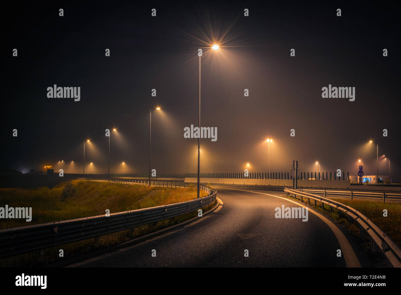 Autoroute sortie au cours d'une nuit brumeuse avec Lampadaires et panneaux sur l'asphalte Banque D'Images
