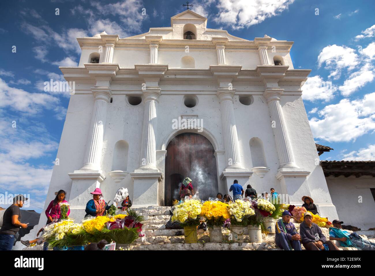 Les gens du coin brûlent des encens et vendent des fleurs jaunes devant Iglesia de Santo Tomas lors d'une journée de marché à Chichichastenango, Guatemala Village Banque D'Images