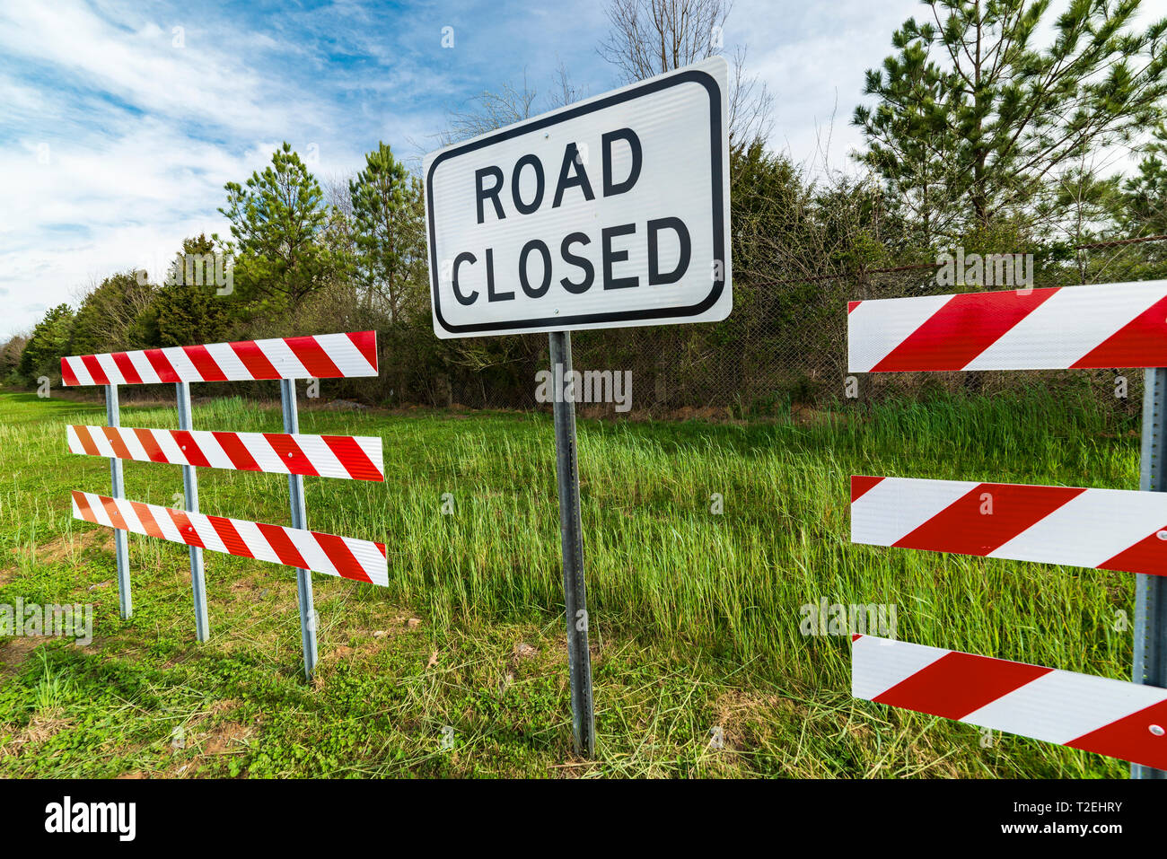 Angle horizontal de rouge et blanc à rayures avec des obstacles d'une route signe clos au milieu d'eux dans une région boisée. Banque D'Images