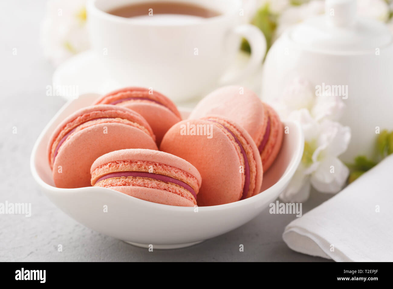 Macarons français rose avec berry le remplissage et un plateau pour le dessert. Fleurs dans l'arrière-plan. Banque D'Images