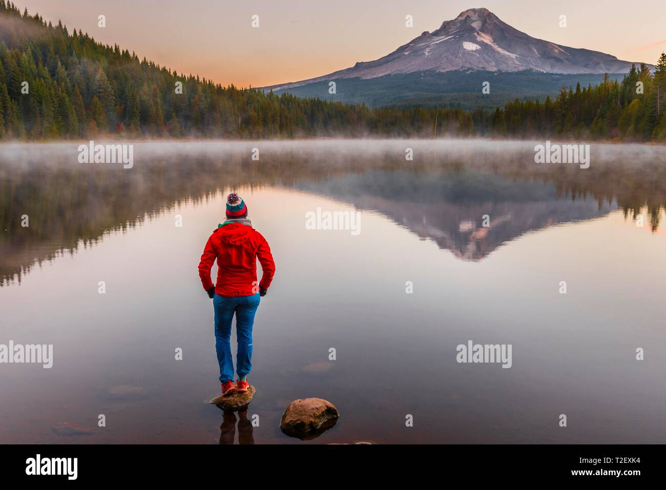 Young woman looking at view du volcan Mt. Le capot avec le reflet dans le lac Trillium lake, au lever du soleil, de l'Oregon, USA Banque D'Images