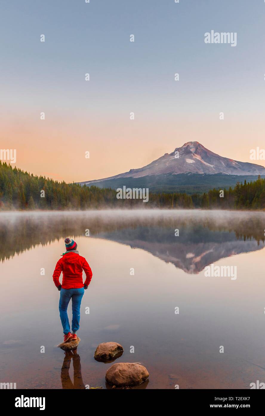 Young woman looking at view du volcan Mt. Le capot avec le reflet dans le lac Trillium lake, au lever du soleil, de l'Oregon, USA Banque D'Images