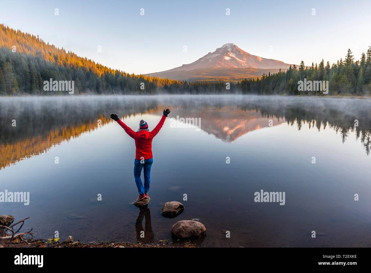 Young woman looking at view du volcan Mt. Le capot avec le reflet dans le lac Trillium lake, au lever du soleil, de l'Oregon, USA Banque D'Images