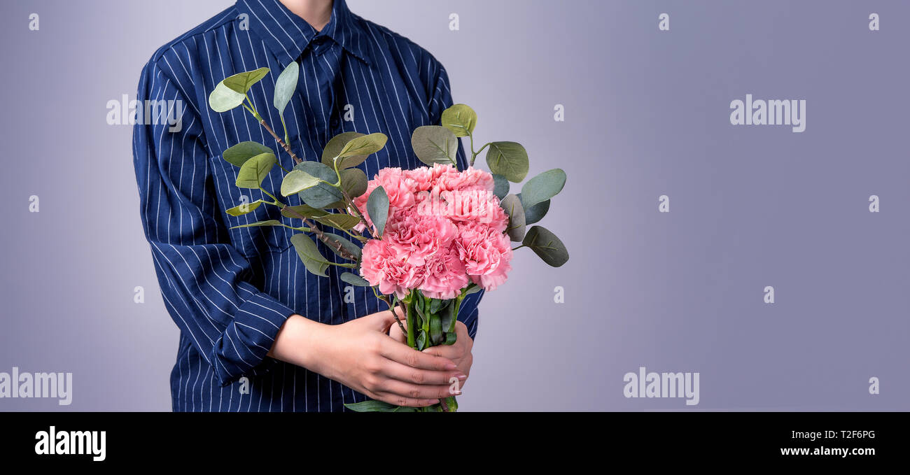 Jeune fille en bleu foncé chemise rayée donnant la main bande de belles  fleurs de couleur rose bébé œillets comme cadeau pour la fête des mères,  concept, fermer Photo Stock - Alamy