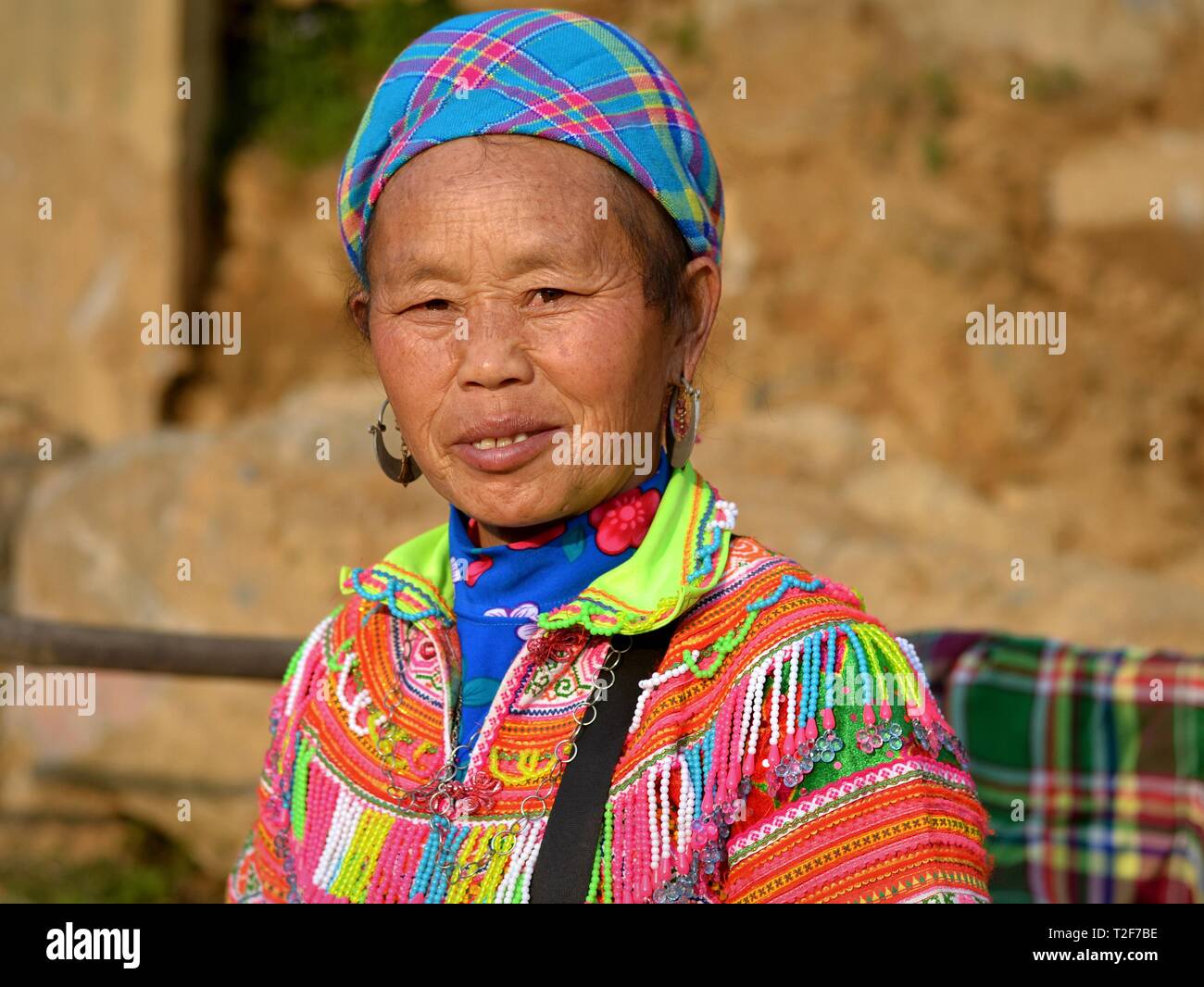 Personnes âgées H'Mong fleurs vietnamiennes hill-tribu femme porte du marché coloré de fleurs brodées, costumes traditionnels H'Mong avec de grandes boucles d'argent. Banque D'Images