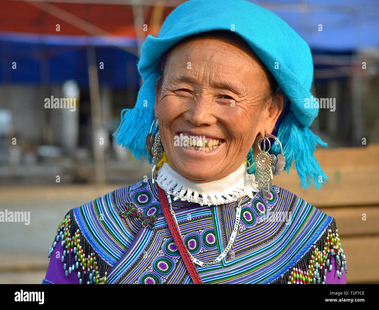 Personnes âgées H'Mong bleu vietnamiens hill-tribu femme avec trois dents en or porte H'Mong traditionnelles en bleu broderie et sourit pour la photo. Banque D'Images