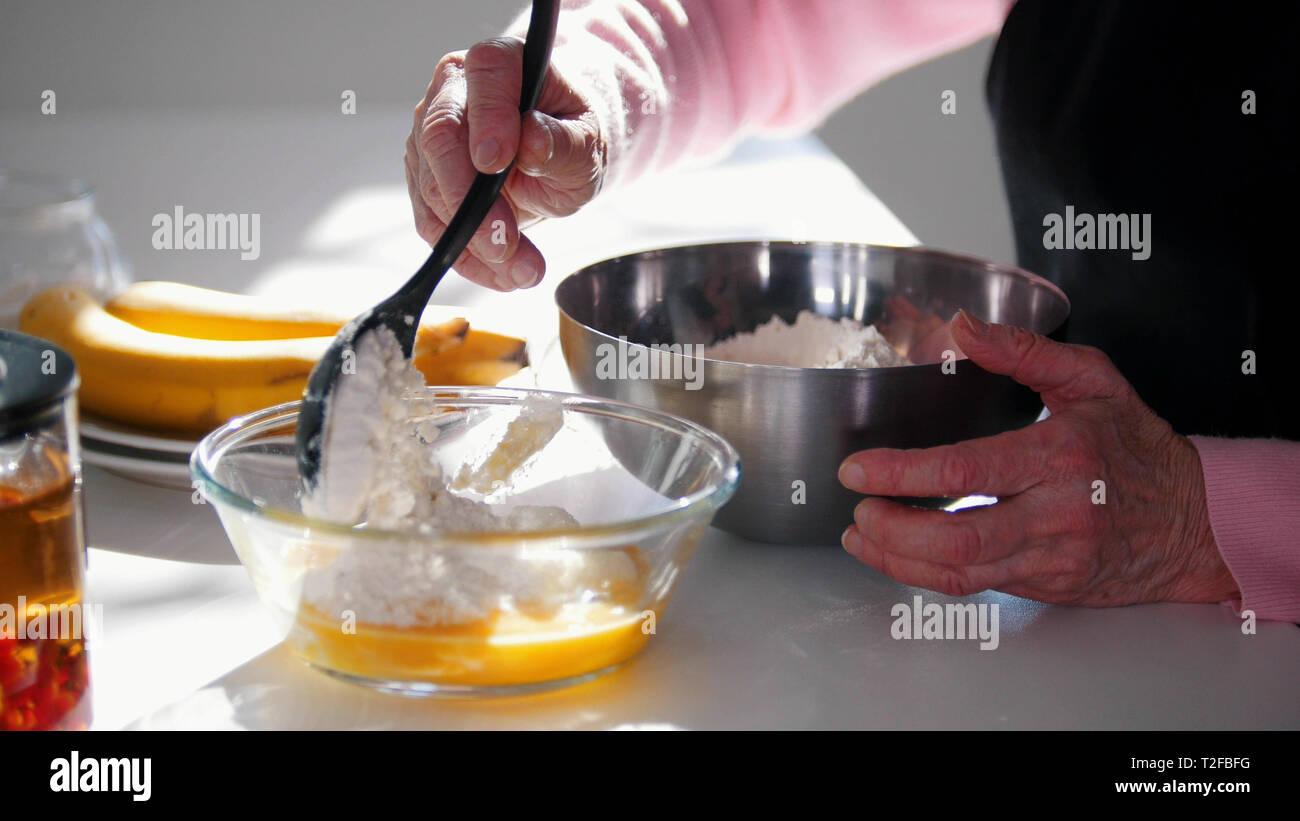 Faire des crêpes. Une vieille femme en ajoutant de la farine dans la pâte. . Milieu shot Banque D'Images