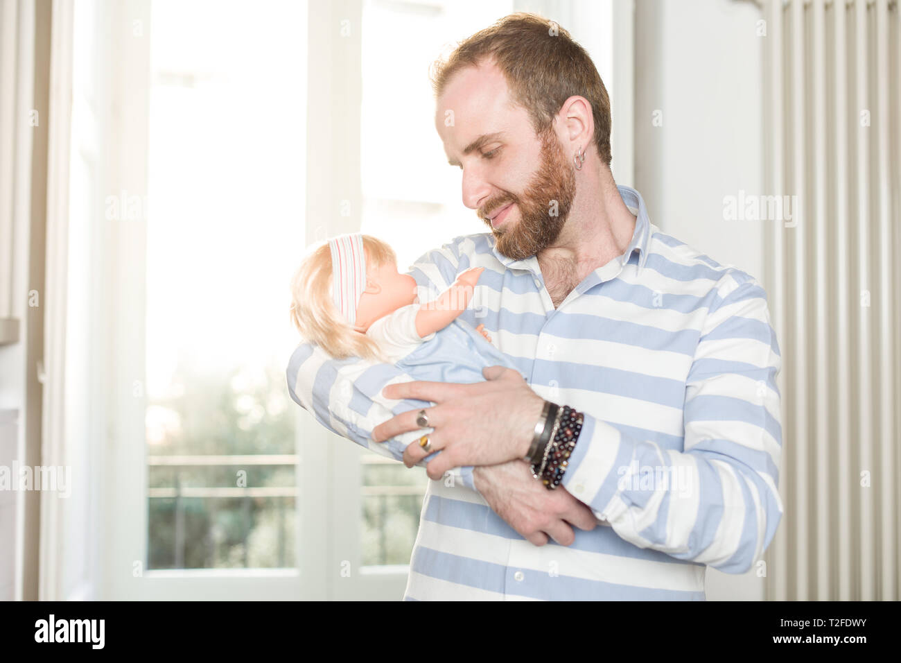 Smiling Redhead Homme avec Barbe, berçant une poupée Banque D'Images