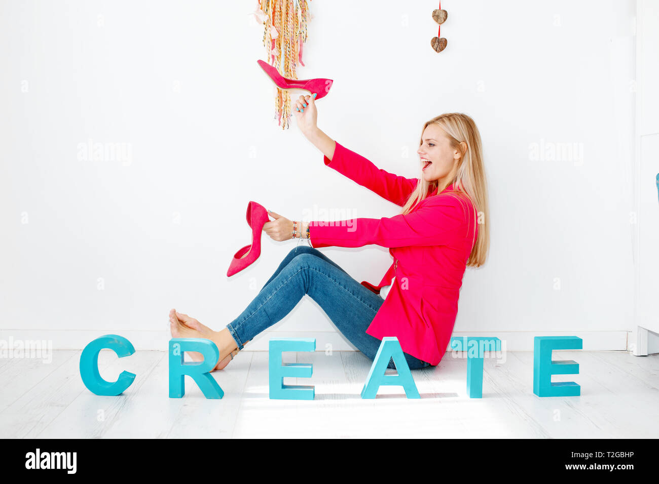 Jeune femme blonde créative jouant sur marbre rose avec des talons hauts et s'amuser Banque D'Images
