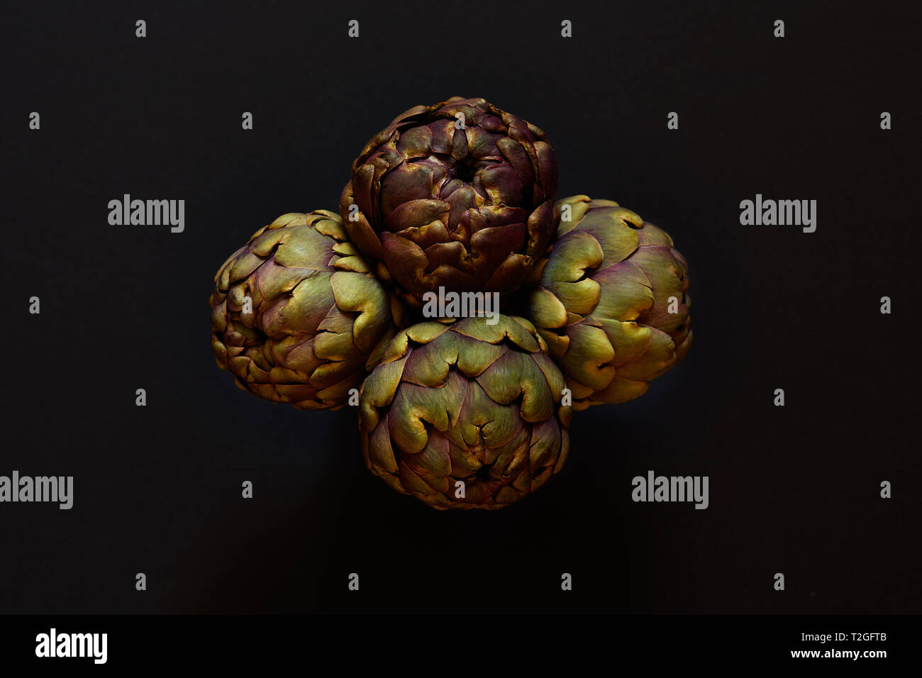Groupe de 4 Artichauts isolées de ci-dessus sur un arrière-plan noir concept flatlay Banque D'Images