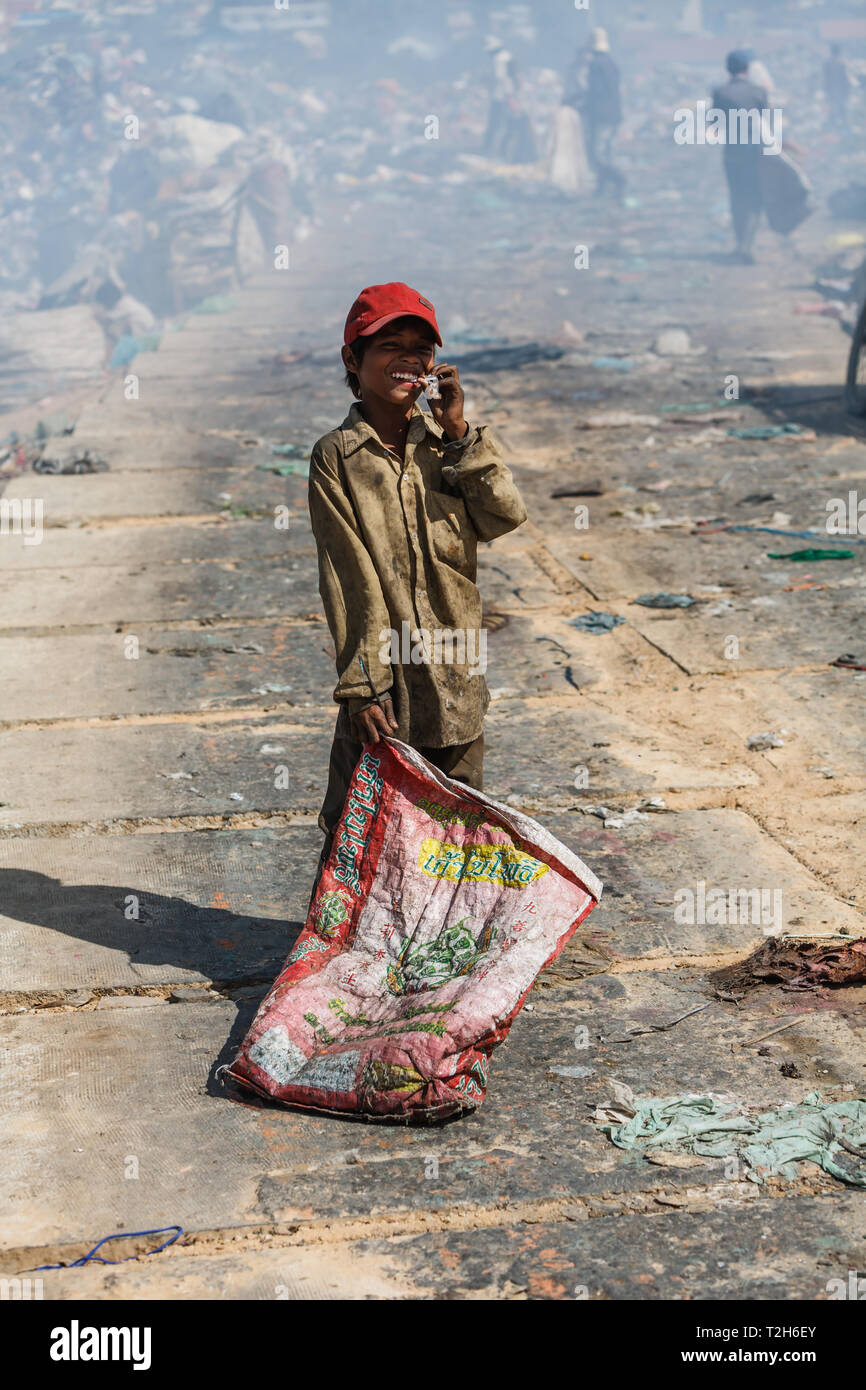 Portrait of a young boy smiling cambodgienne avec casquette de baseball rouge sac de transport pour mettre trouvé des trésors de la ville de vidage Banque D'Images