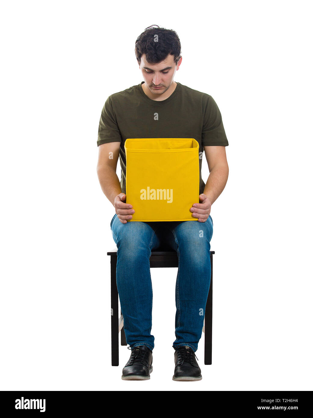 Portrait d'un curieux casual guy assis sur une chaise à l'intérieur d'une boîte jaune isolé sur fond blanc. Banque D'Images