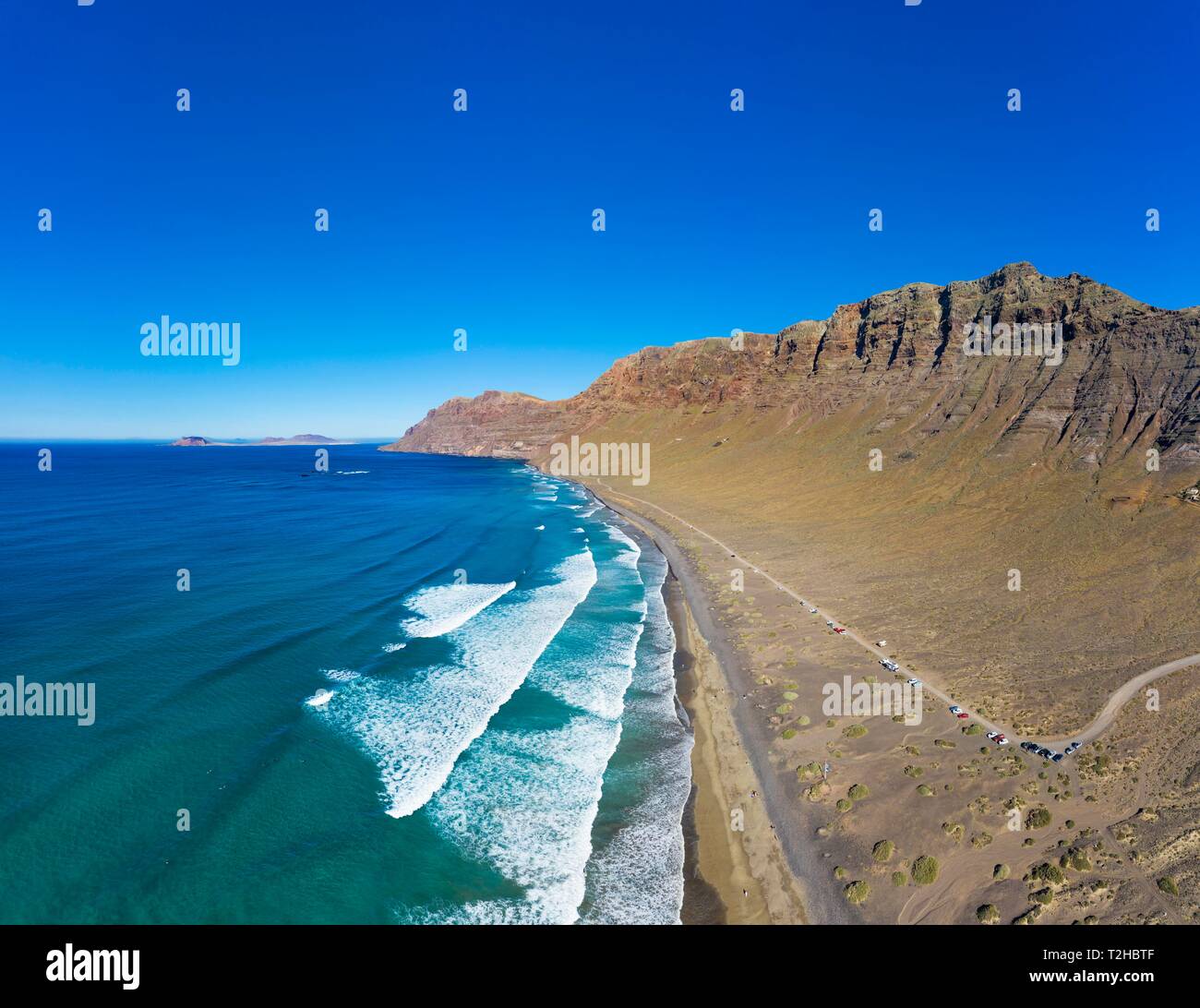 Vue sur la plage Playa Famara avec gamme de montagne Risco de Famara, à Caleta de Famara, derrière l'île de La Graciosa, drone abattu, Lanzarote, Canaries Banque D'Images