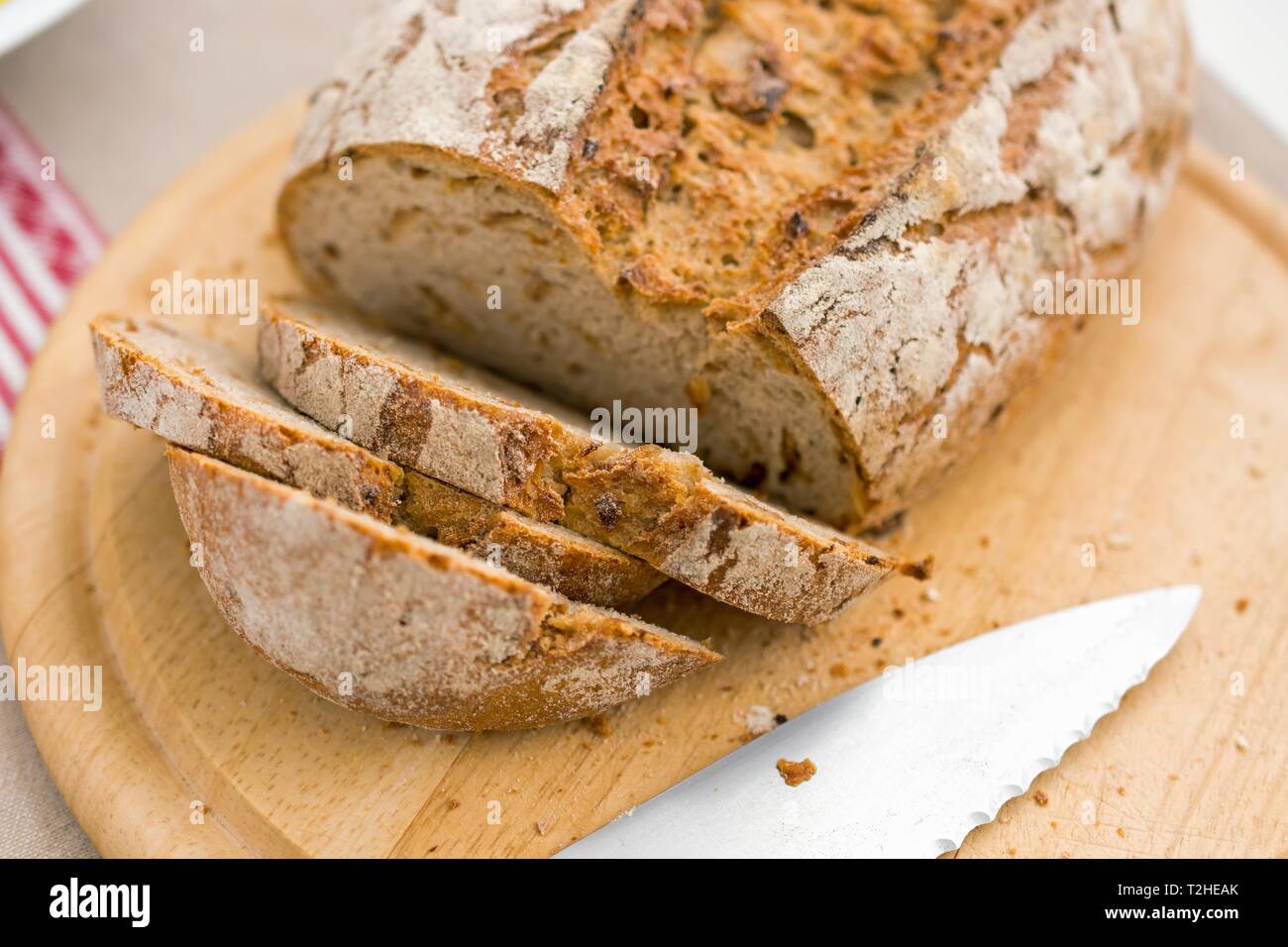 Couper l'oignon pain sur une planche en bois avec couteau à pain, Landhauskuche, Allemagne Banque D'Images