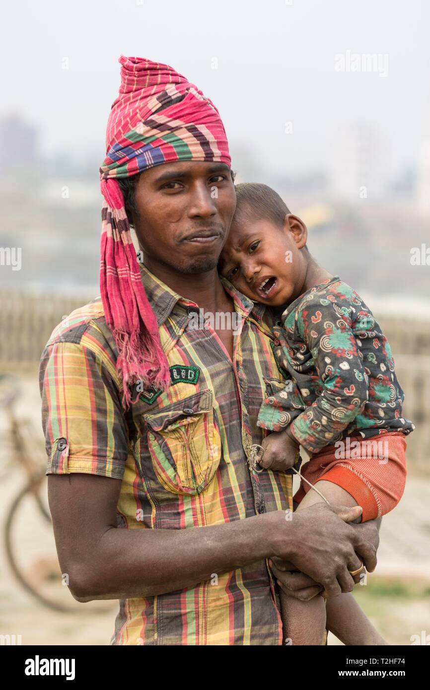Homme avec enfant en pleurs sur son bras, Dhaka, Bangladesh Banque D'Images