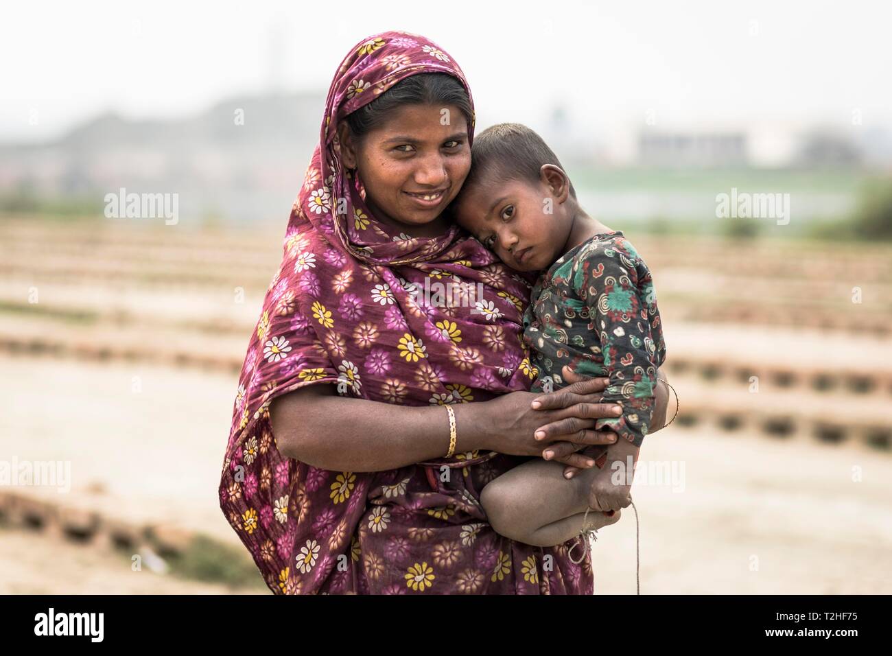 Femme souriante avec un petit enfant sur son bras, Dhaka, Bangladesh Banque D'Images