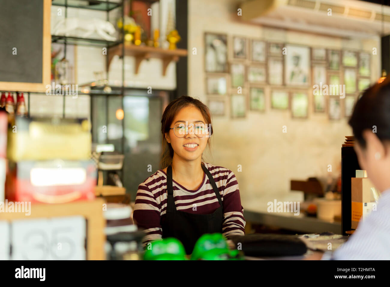 Jeune femme de la barista avec smile face au comptoir bar in cafe Banque D'Images