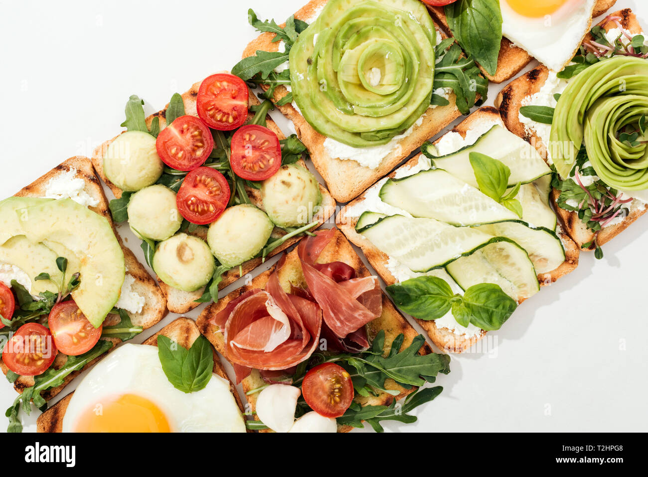 Vue de dessus de toasts avec couper les légumes, œufs frits et de prosciutto sur blanc Banque D'Images