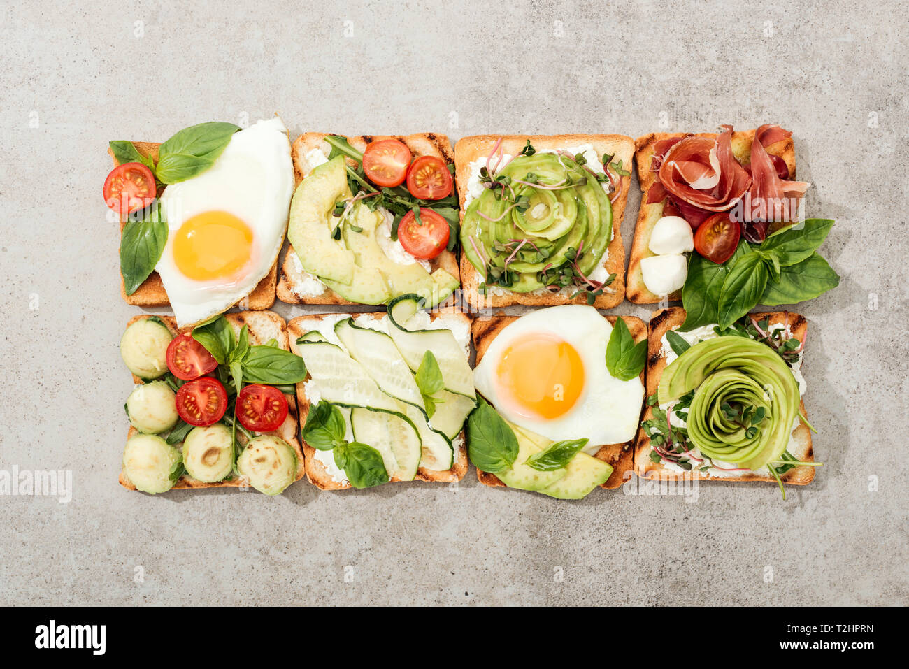 Vue de dessus de toasts avec des légumes, œufs frits et de prosciutto sur la surface texturée Banque D'Images