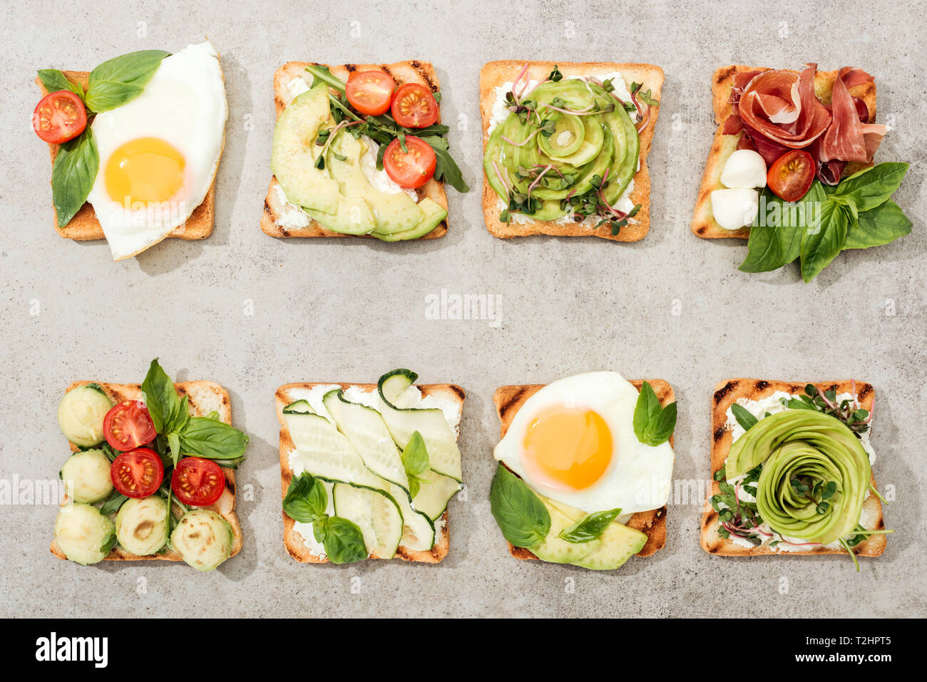 Vue de dessus de toasts avec des légumes, œufs frits et de prosciutto sur la surface texturée Banque D'Images