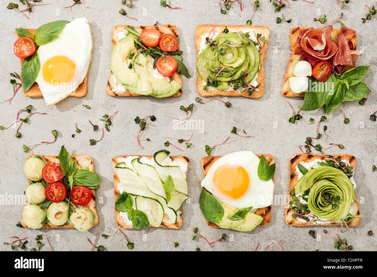 Vue de dessus de toasts avec des légumes, œufs frits et de prosciutto sur la surface texturée Banque D'Images