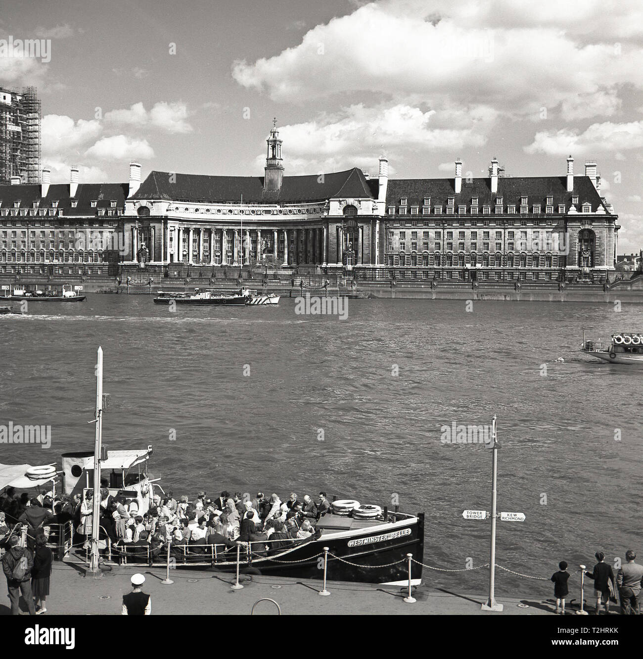 Années 1960, historique, photo montre Westminster Pier, avec les gens entassés sur un bateau de tourisme, 'Belle' de Westminster, Londres, Angleterre, Royaume-Uni, avec le County Hall, ancienne maison du London County Council (LCC) Le grand bâtiment assis sur la berge d'en face. Banque D'Images